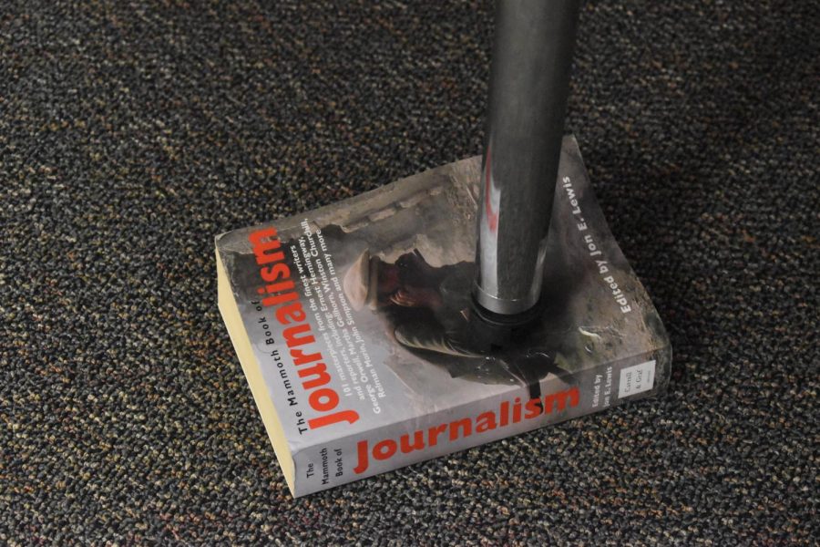A journalism book being used to balance a table.