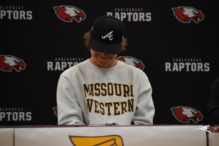 Baseball signee Jackson Bryant looks down at his signing papers for Missouri Western State University as his coach speaks of his stats and strengths as a player.
