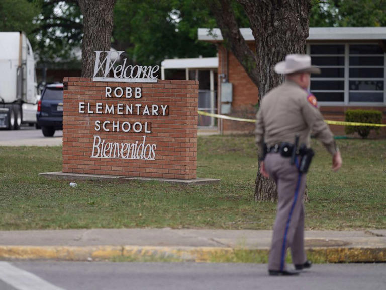 A police officer walks in front of Robb Elementary in Uvalde, TX.
