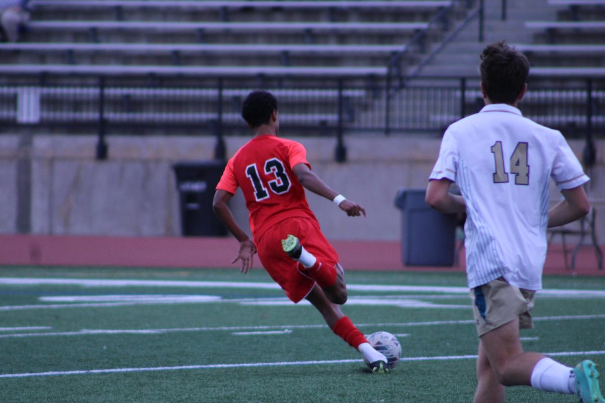 Junior Adam Keresemo kicking the ball to a nearby teammate.