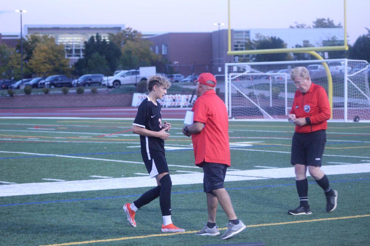 Junior Drew Tullio talks to his coach on the side of the field to gain some helpful tips.