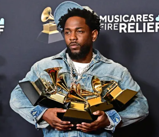 Kendrick Lamar holding his 5 Grammy Awards.