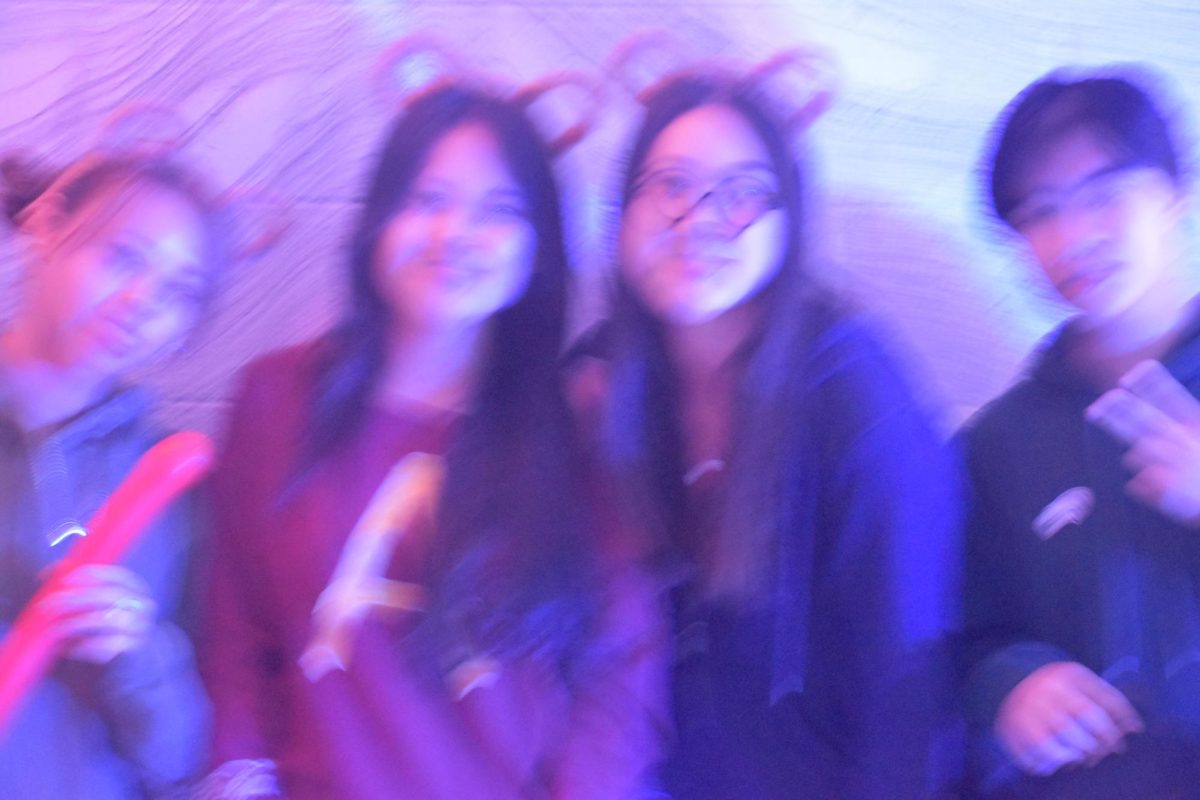 Juniors smile for a blurred, dark, Photo Booth in the cafeteria hallway, Yearbook and Nest Network provided with several Polaroid cameras token by our photography experts.